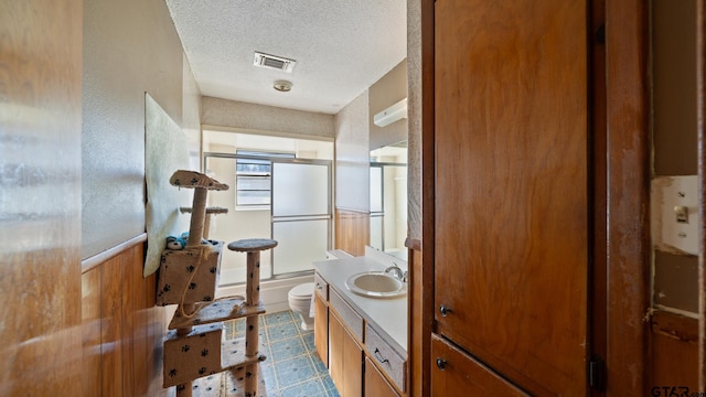 full bathroom with shower / bath combination with glass door, vanity, a textured ceiling, and toilet