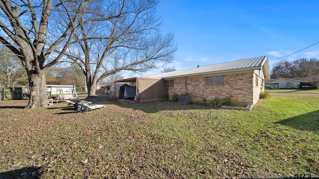 rear view of property with central AC unit and a lawn