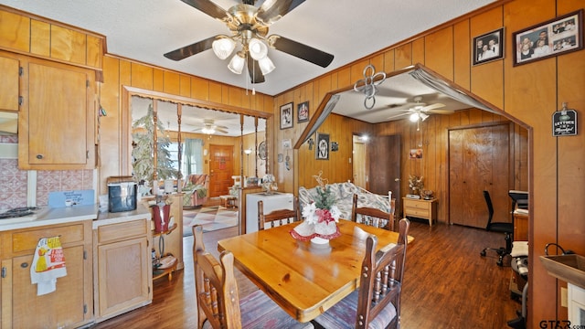 dining room with ceiling fan, wood walls, dark hardwood / wood-style floors, and a textured ceiling