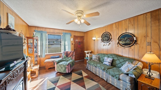 living room featuring ceiling fan, dark wood-type flooring, and wooden walls