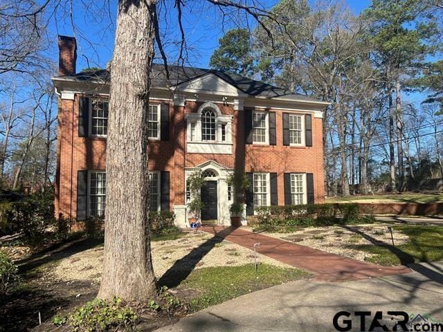 view of front of property featuring brick siding and a chimney