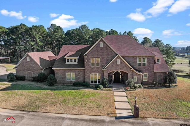 view of front of property with brick siding, a front lawn, and a shingled roof