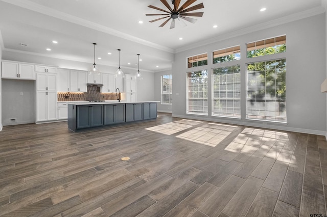 unfurnished living room with baseboards, dark wood-style flooring, a sink, and recessed lighting