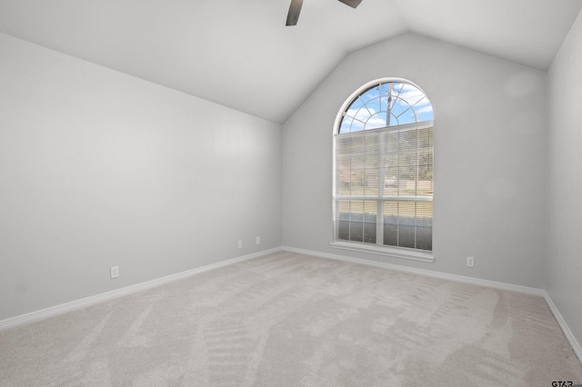 carpeted spare room with vaulted ceiling, baseboards, and ceiling fan