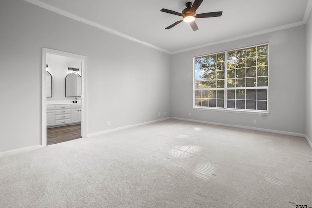 unfurnished bedroom with crown molding, a sink, ensuite bathroom, carpet floors, and baseboards