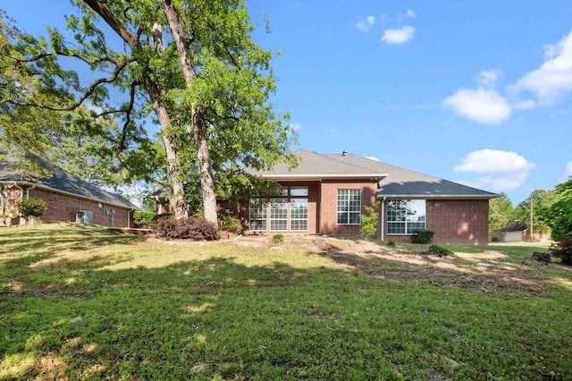 rear view of house with a lawn and brick siding