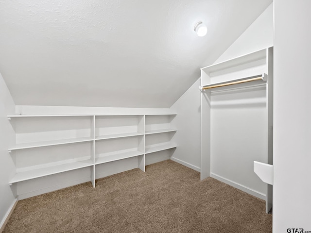 spacious closet featuring vaulted ceiling and light colored carpet