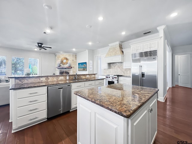 kitchen featuring white cabinetry, a kitchen island, premium appliances, and kitchen peninsula