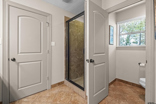 bathroom featuring tile patterned floors, baseboards, a shower stall, and toilet