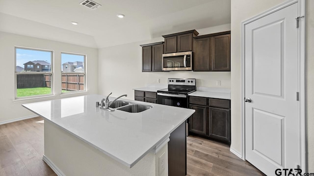 490 Burnett Trl, Canton, TX 75103 - kitchen featuring stainless steel appliances, light wood-style flooring, light countertops, dark brown cabinetry, and a center island with sink