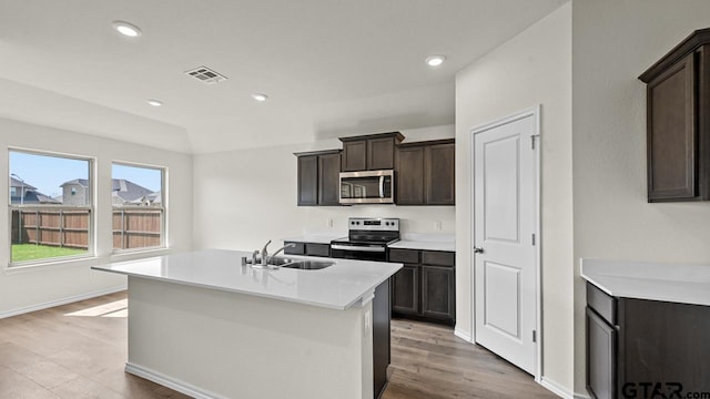 490 Burnett Trl, Canton, TX 75103 - kitchen with stainless steel appliances, light countertops, a center island with sink, dark brown cabinets, and light wood finished floors