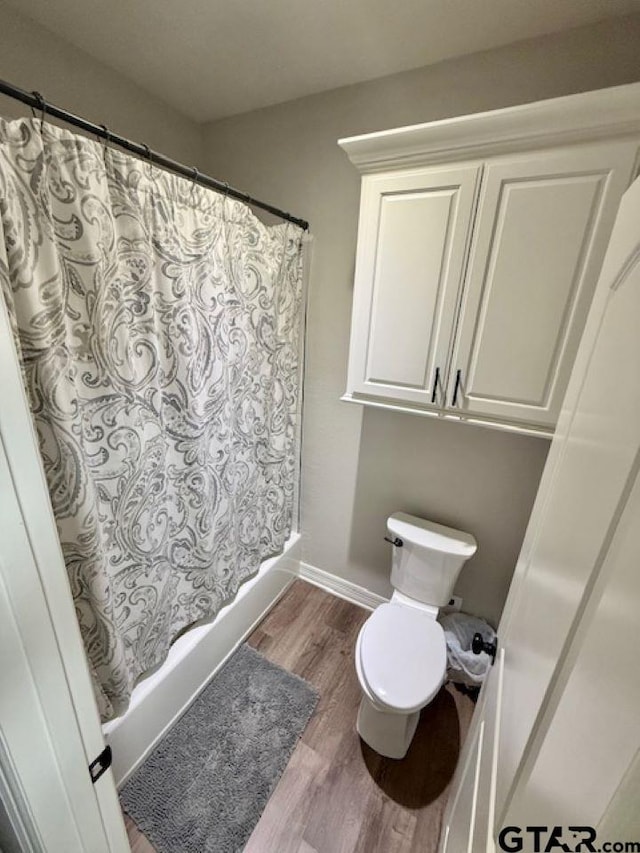 bathroom featuring toilet, wood-type flooring, and shower / tub combo with curtain