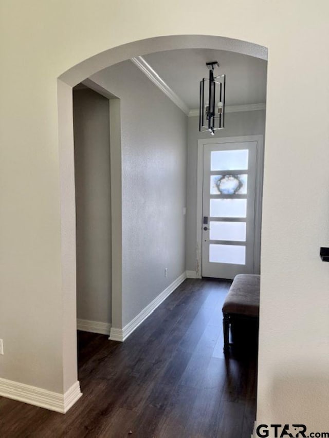 foyer featuring dark hardwood / wood-style floors, ornamental molding, and a chandelier