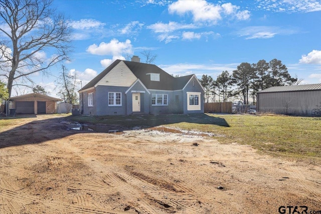 view of front of home featuring a front lawn, a garage, and an outbuilding