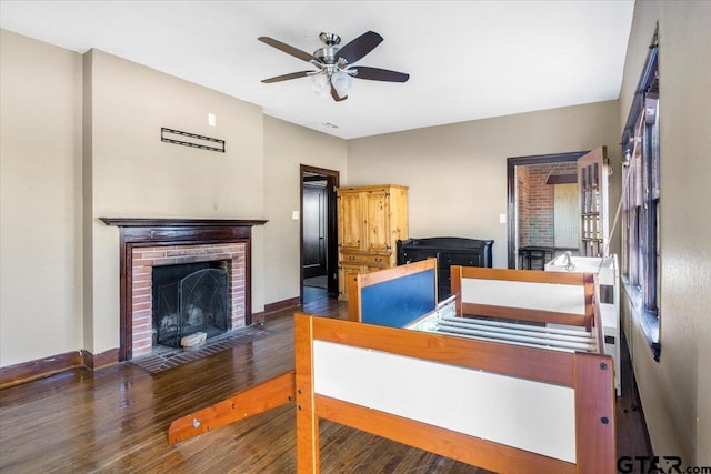 bedroom featuring a fireplace, ceiling fan, and dark hardwood / wood-style floors