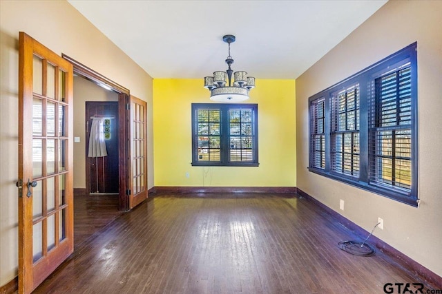 unfurnished room featuring french doors, dark hardwood / wood-style flooring, a healthy amount of sunlight, and a notable chandelier