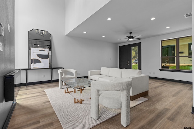 living room with ceiling fan with notable chandelier and wood-type flooring