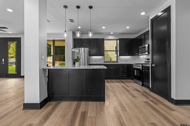 kitchen with light stone countertops, ceiling fan, light hardwood / wood-style flooring, and appliances with stainless steel finishes