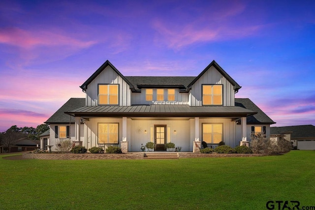 back of property featuring board and batten siding, a standing seam roof, covered porch, and a lawn