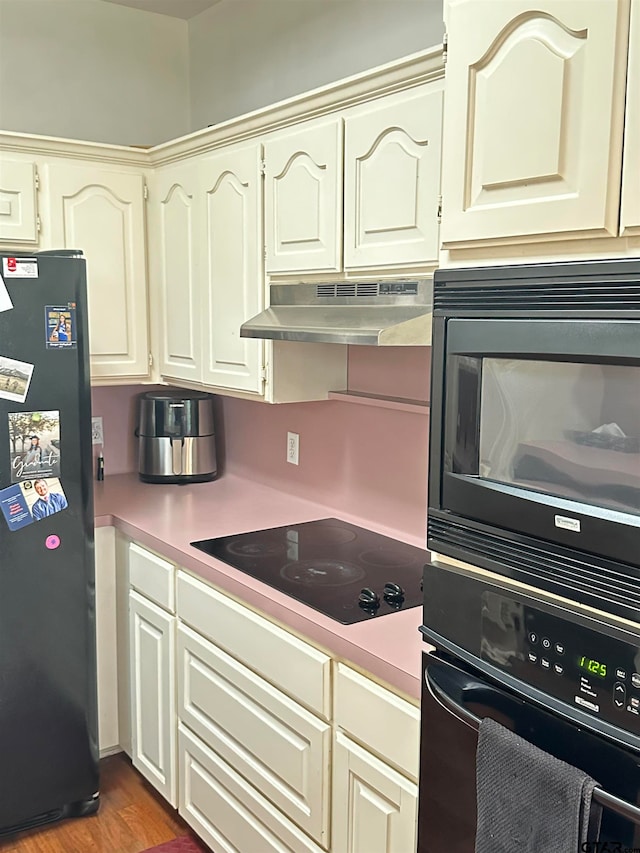 kitchen with black appliances and dark hardwood / wood-style floors