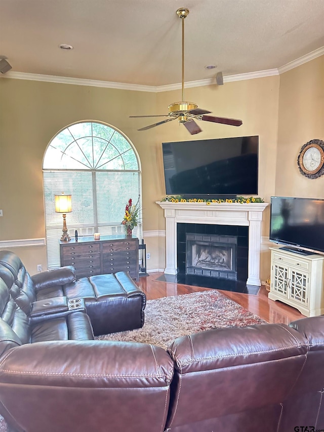 living room featuring a fireplace, hardwood / wood-style flooring, ceiling fan, and ornamental molding