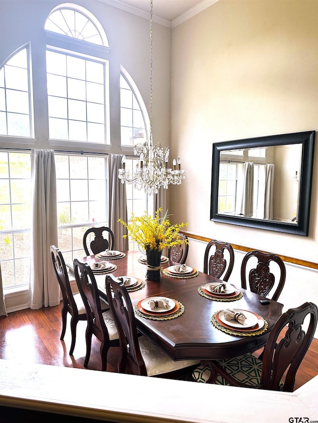 dining room with hardwood / wood-style floors, a notable chandelier, and crown molding