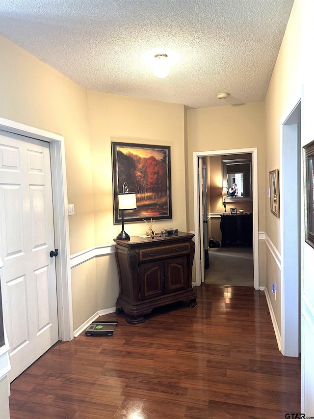 hallway with a textured ceiling and dark hardwood / wood-style floors