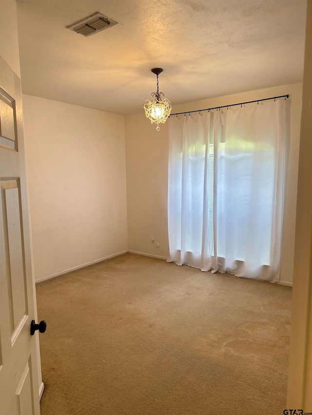 spare room with light colored carpet and a textured ceiling