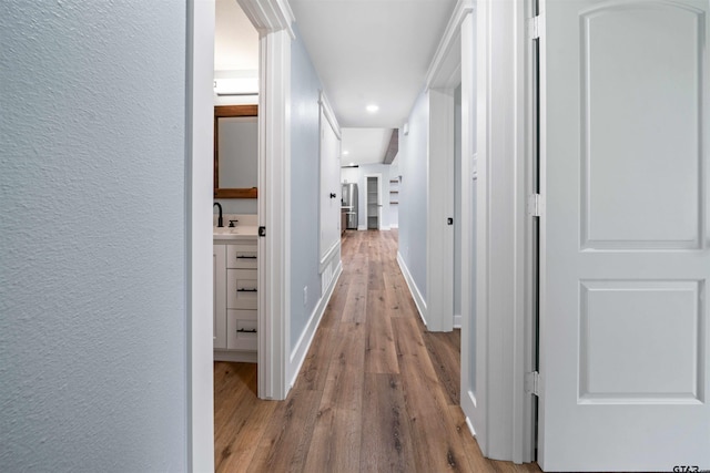 corridor featuring sink and light hardwood / wood-style flooring