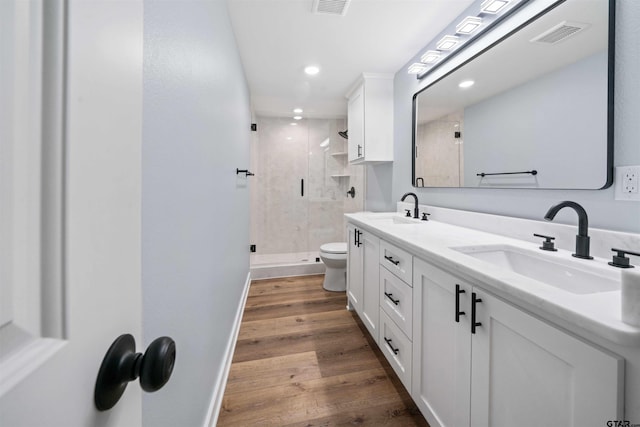 bathroom with toilet, vanity, hardwood / wood-style flooring, and a shower with shower door