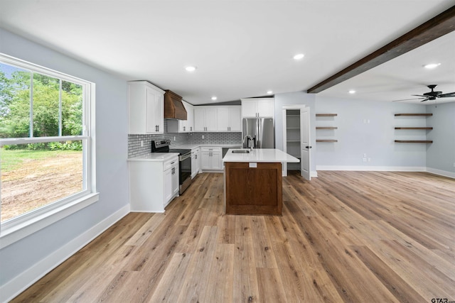 kitchen with stainless steel appliances, custom range hood, a center island, white cabinets, and light wood-type flooring