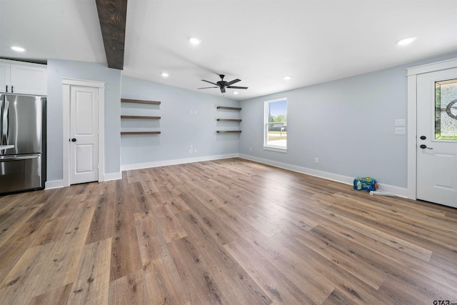 unfurnished living room featuring light wood-type flooring, ceiling fan, and beamed ceiling