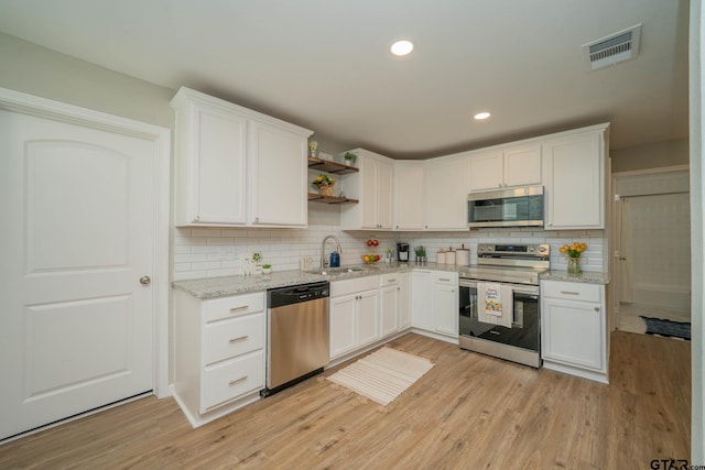 1021 N Montgomery St, Gilmer, TX 75644 - kitchen featuring stainless steel appliances, open shelves, white cabinets, light wood finished floors, and recessed lighting