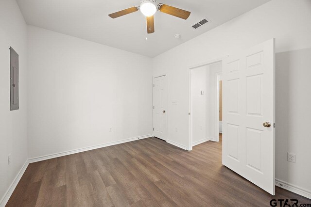 unfurnished bedroom featuring baseboards, electric panel, visible vents, and dark wood-style flooring