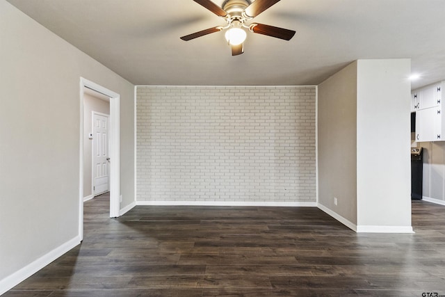 unfurnished room featuring ceiling fan, dark hardwood / wood-style floors, and brick wall