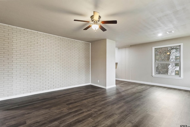 unfurnished room featuring ceiling fan, dark hardwood / wood-style flooring, and brick wall