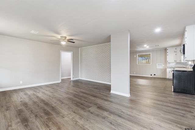 unfurnished living room featuring ceiling fan, sink, and hardwood / wood-style floors