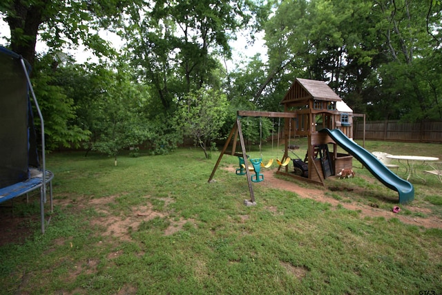 view of jungle gym featuring fence, a yard, and a trampoline
