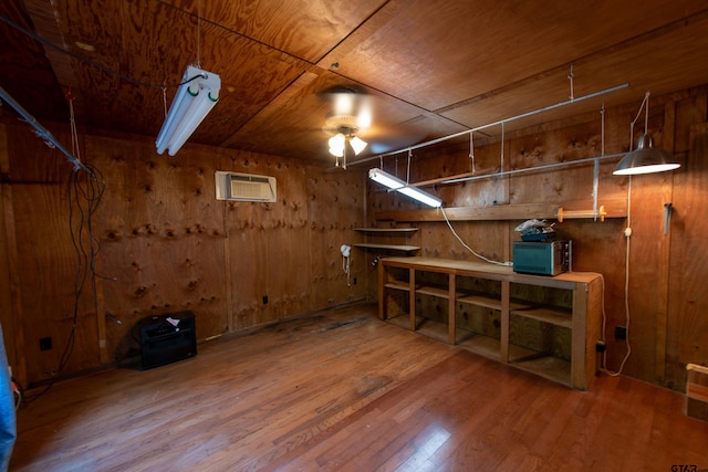 basement with a wall unit AC, wood ceiling, wooden walls, hardwood / wood-style flooring, and ceiling fan