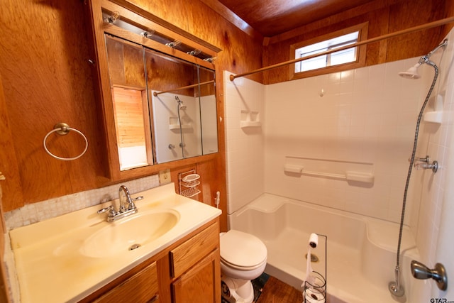 bathroom with toilet, vanity, wooden walls, and tiled shower