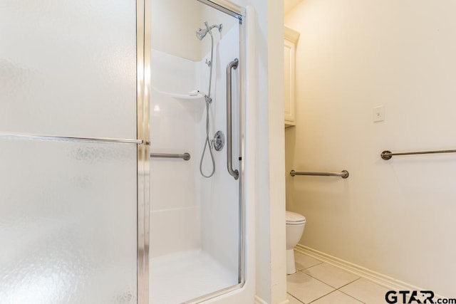 full bathroom with toilet, a stall shower, tile patterned flooring, and baseboards