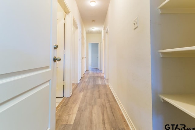 hall featuring light wood-type flooring and baseboards