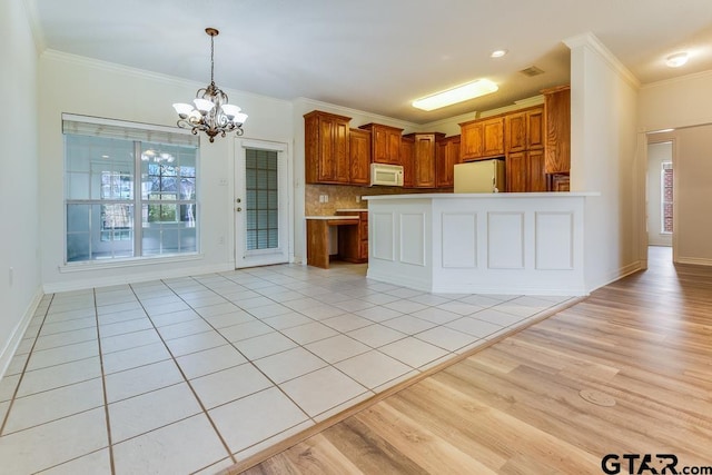 3425 Iberville Dr, Tyler, TX 75701 - kitchen with white appliances, light wood-style flooring, a chandelier, crown molding, and brown cabinetry