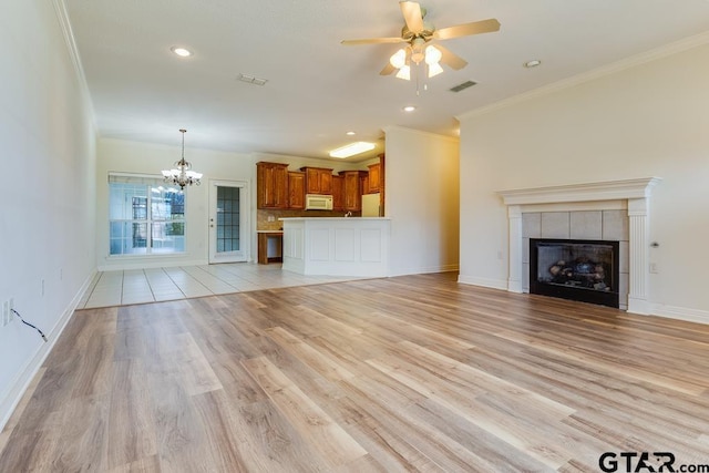 unfurnished living room with light wood finished floors, visible vents, ornamental molding, and a tiled fireplace