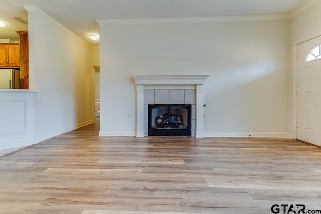 unfurnished living room with light wood-style floors, a tile fireplace, and crown molding