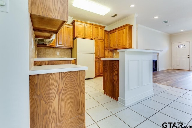 kitchen with light tile patterned floors, visible vents, ornamental molding, freestanding refrigerator, and light countertops