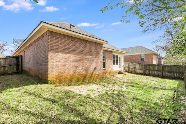 rear view of property with a yard, brick siding, and a fenced backyard