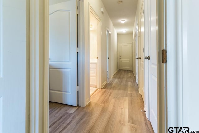 hall with light wood-style floors and baseboards