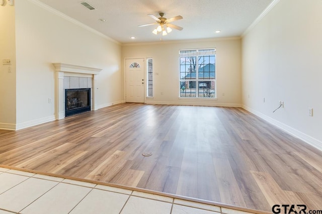 unfurnished living room featuring light wood-style floors, a tile fireplace, visible vents, and crown molding