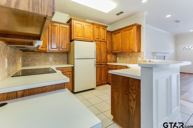 kitchen with freestanding refrigerator, light countertops, a peninsula, and black electric cooktop